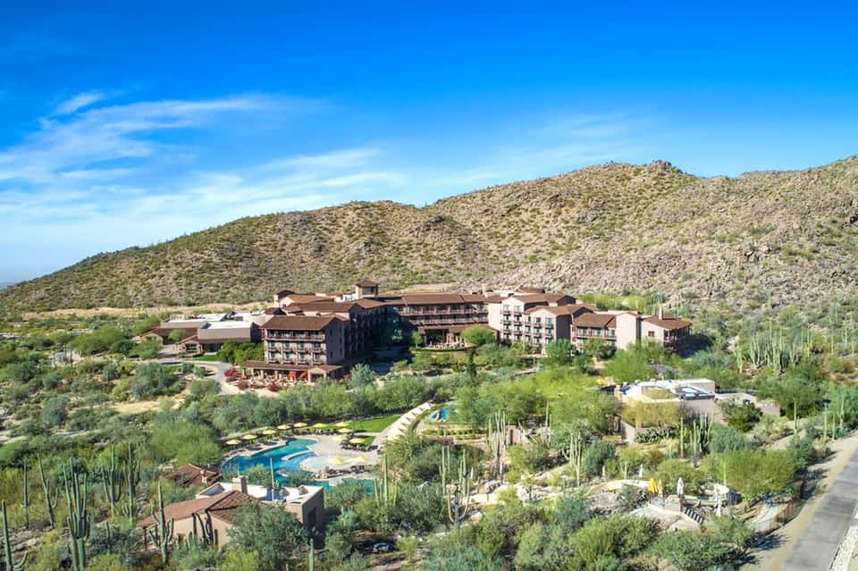 Desert resort nestled in hillside landscape with pool, cacti, and warm earth-tone architecture