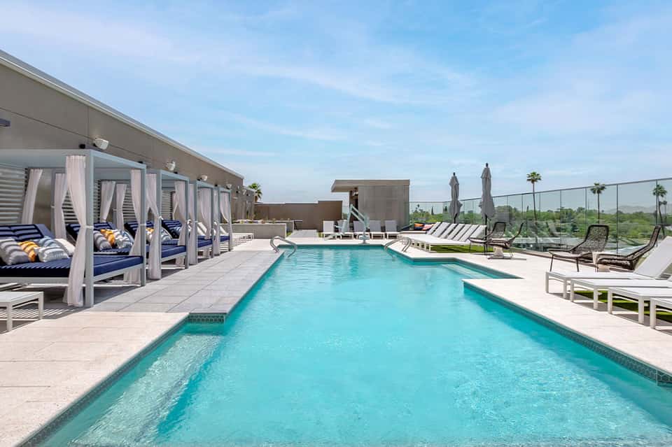 Rooftop pool with cabanas and lounge chairs overlooking manicured grounds and distant landscape
