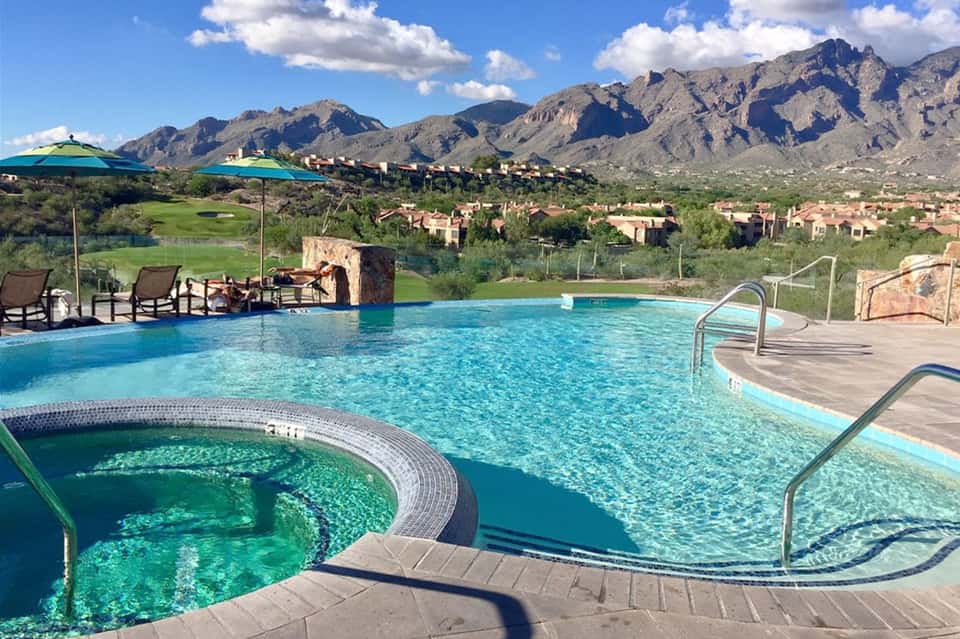 Luxury resort pool with mountain backdrop, spa area, lounge chairs, and desert landscape