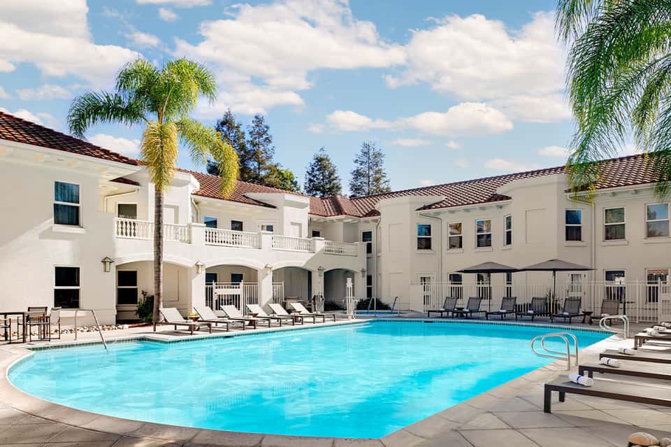 Resort courtyard pool with white Spanish colonial architecture and palm trees
