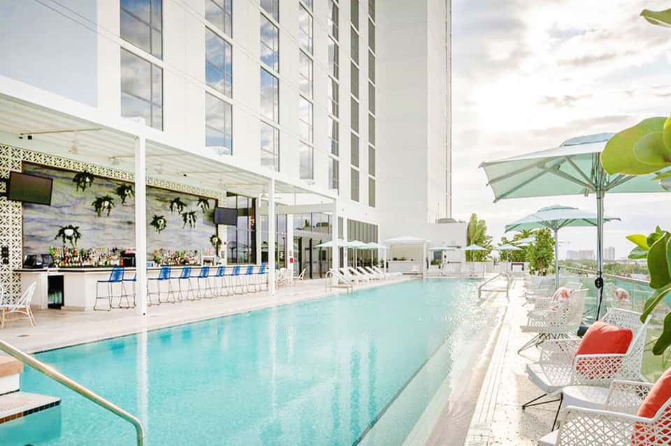 Contemporary indoor pool with bar, loungers, green umbrellas and floor-to-ceiling windows