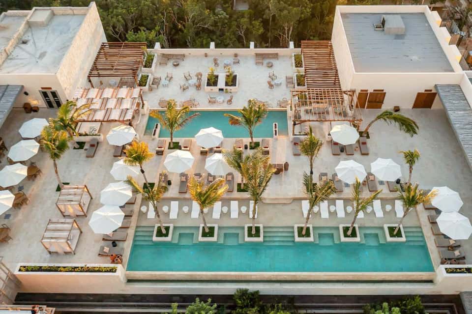 Aerial view of resort pool complex with white umbrellas and modern architecture