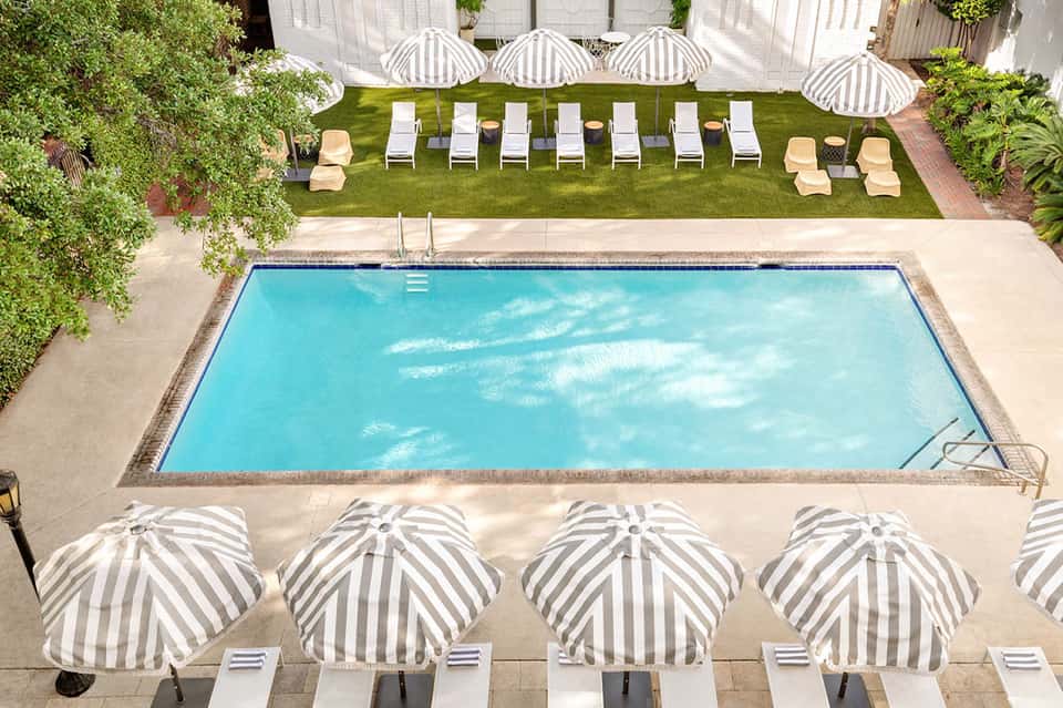 Aerial view of rectangular pool with striped umbrellas, lounge chairs, and manicured lawn