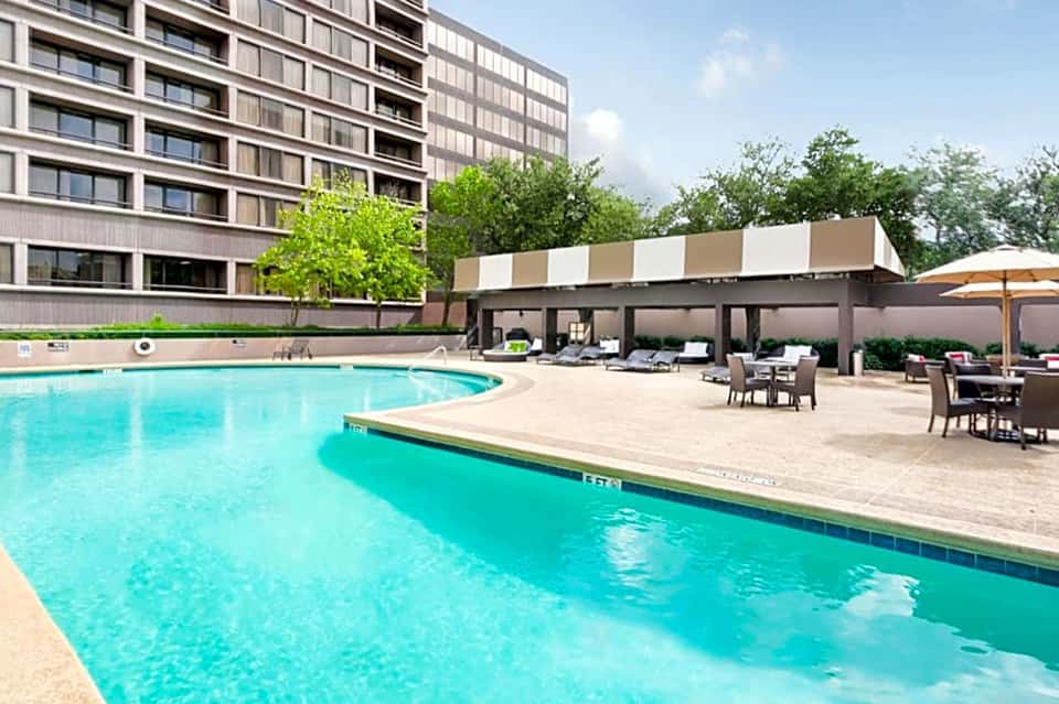 Contemporary resort pool with turquoise water, lounge chairs, umbrellas, and covered seating areas