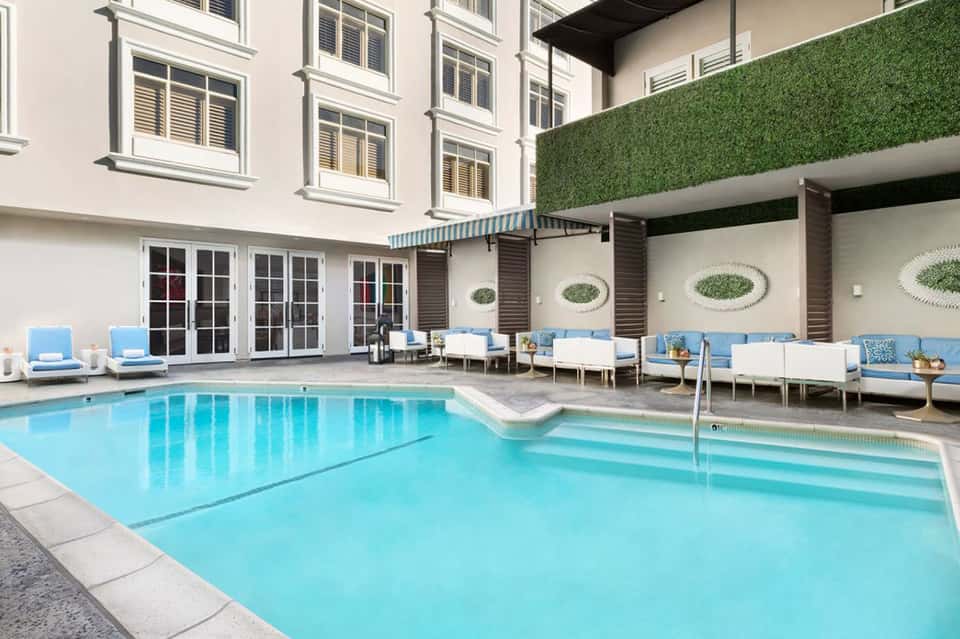 Indoor-outdoor hotel pool with blue lounge chairs and modern architecture