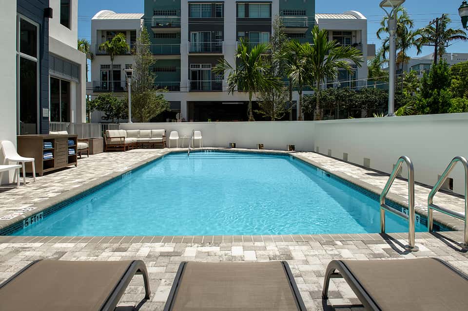 Rectangular pool with lounge chairs and modern residential building backdrop
