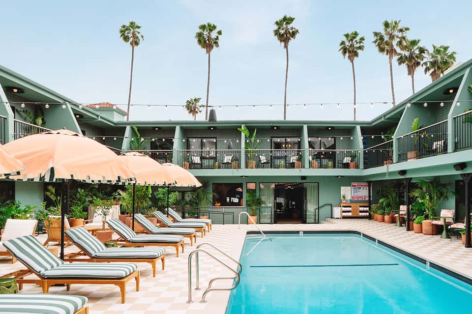 Resort pool courtyard with striped lounge chairs and green building architecture