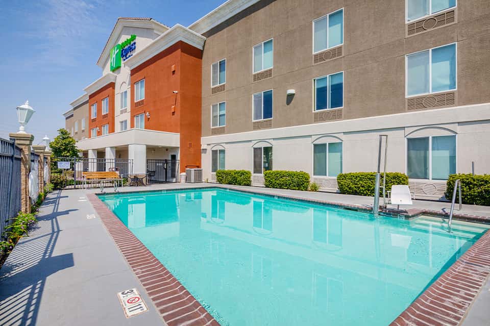 Rectangular outdoor pool with turquoise water flanked by modern hotel building and landscaping