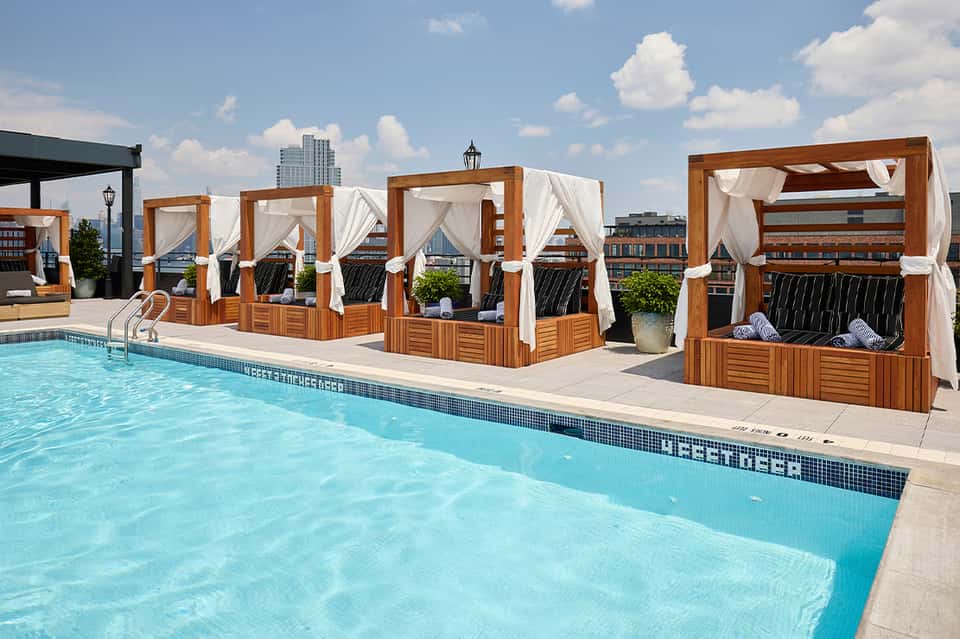 Rooftop pool with wooden cabanas and city skyline view
