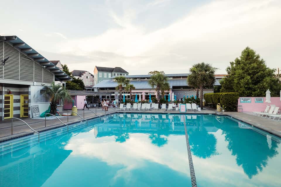 Olympic-sized lap pool reflecting clouds with resort buildings, palm trees, and lane dividers