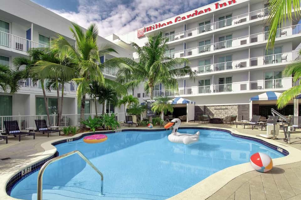 Garden Inn resort courtyard with palm trees, swimming pool, and multi-story hotel building