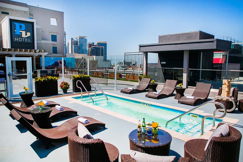 Rooftop pool at urban hotel with city skyline views, lounge chairs, and modern cabana