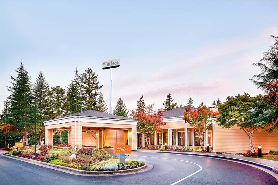 Hotel entrance with modern orange and white architecture surrounded by autumn foliage and trees