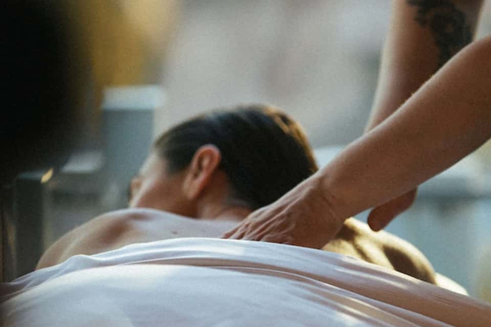 Spa therapist providing massage treatment to client on white table
