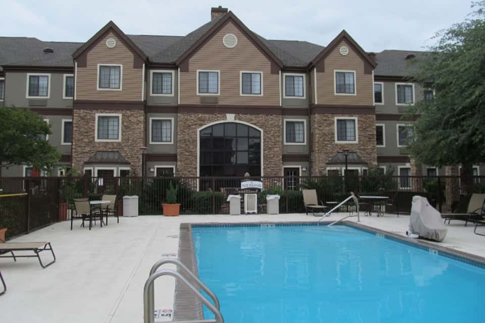 Outdoor pool area with brick building, lounge chairs, and white concrete deck at residential resort