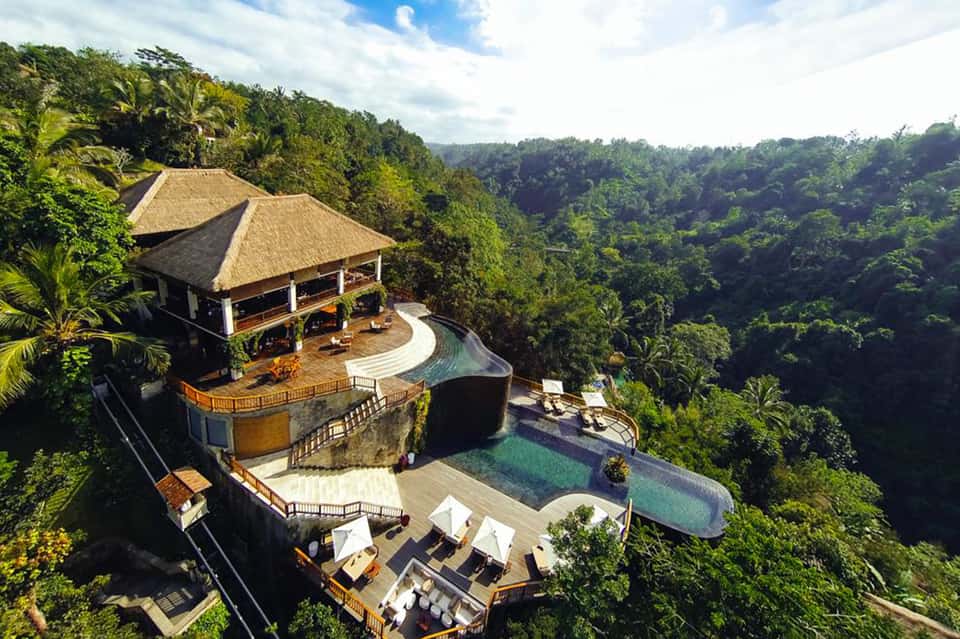 Luxury clifftop villa with infinity pool, thatched roof, and jungle forest views