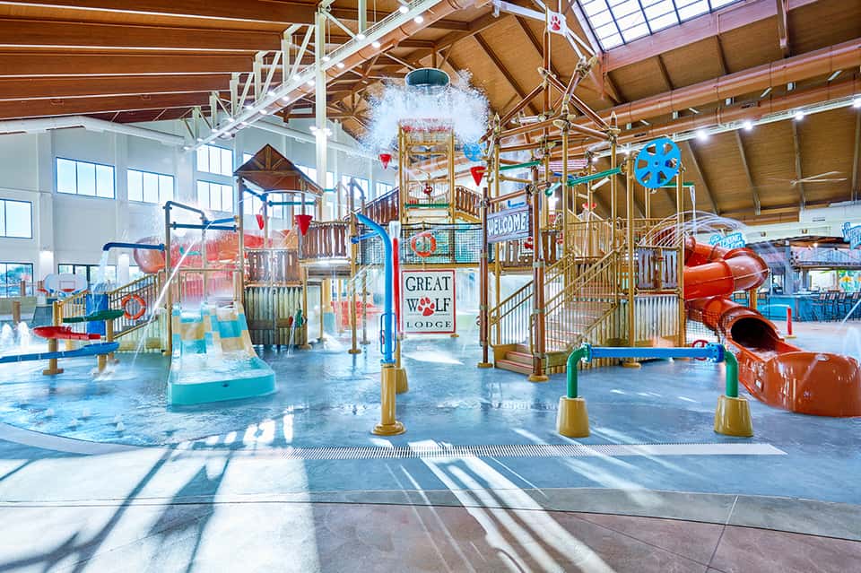 Indoor water park with slides, splash area, and colorful play structures under skylights