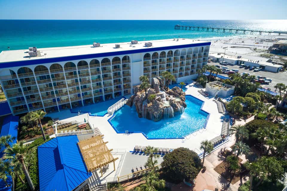 Large beachfront resort with distinctive blue architectural features, multiple pool areas, and ocean backdrop
