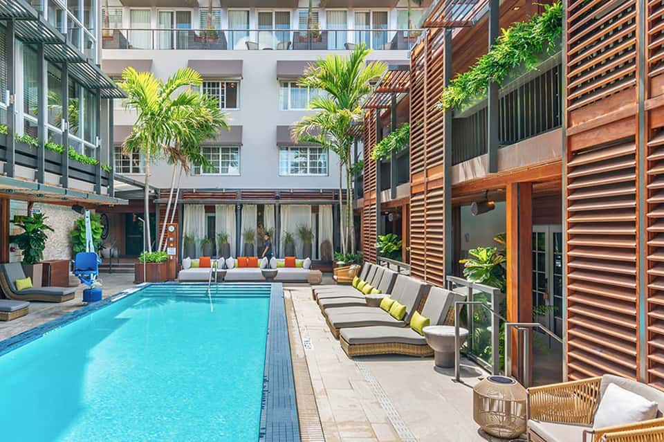Urban resort courtyard with rectangular lap pool, wooden screens, and lounge seating