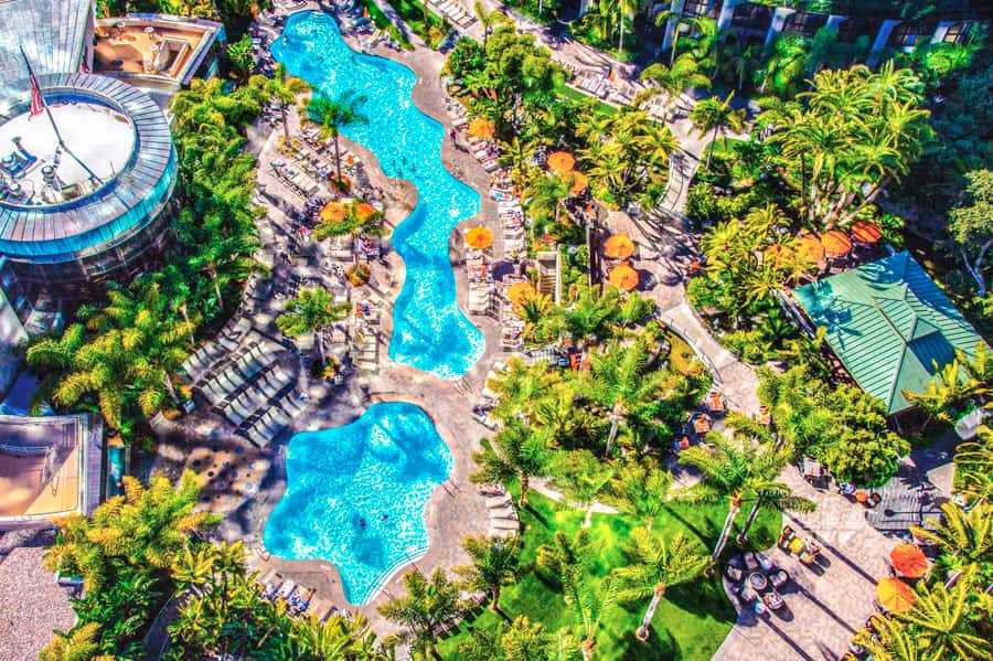 Aerial view of resort with multiple turquoise pools surrounded by palm trees and lounge chairs