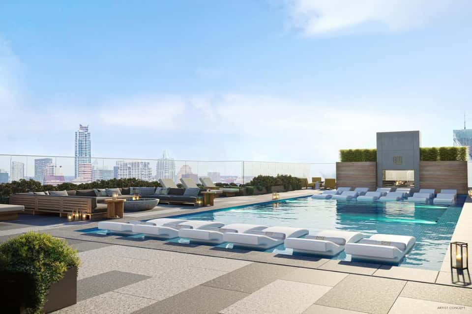 Rooftop pool with white loungers, city skyline views, and modern architectural elements
