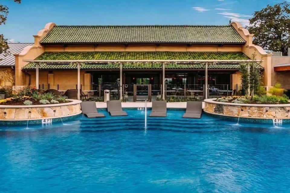 Luxury resort pool with loungers and Asian-inspired architecture featuring green tile roofing