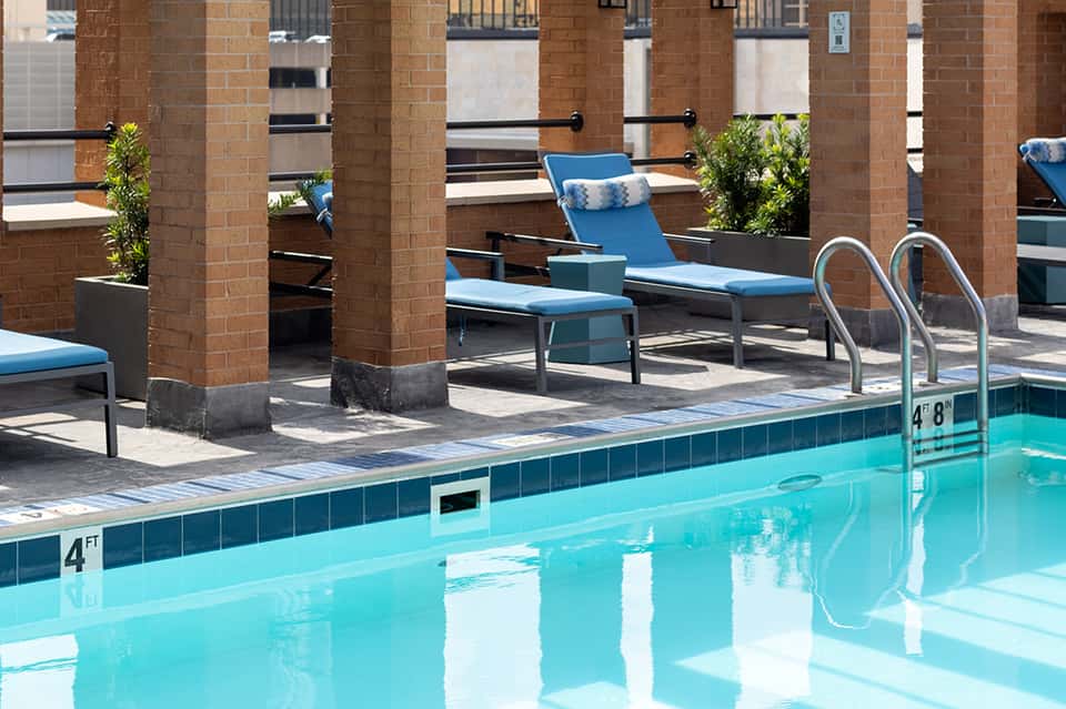 Blue lounge chairs by indoor pool surrounded by brick columns and glass windows