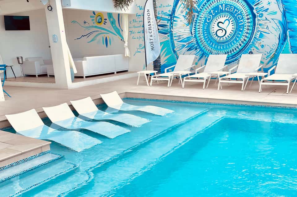 Indoor lap pool with white loungers and blue wave mural artwork on walls