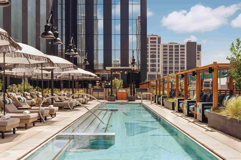 Rooftop pool deck with lounge chairs, umbrellas, and city skyline views