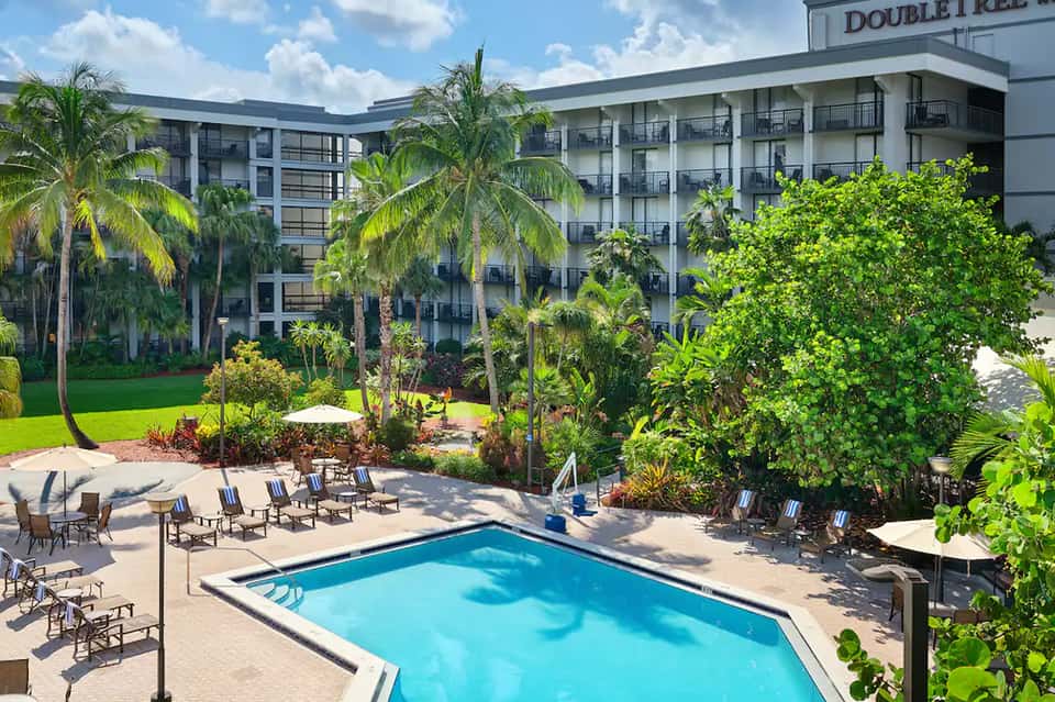 DoubleTree hotel exterior with four-story building overlooking tropical courtyard pool and palm trees