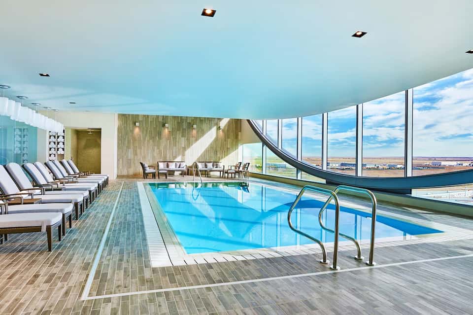 Indoor swimming pool with lounge chairs and expansive windows overlooking a scenic landscape view