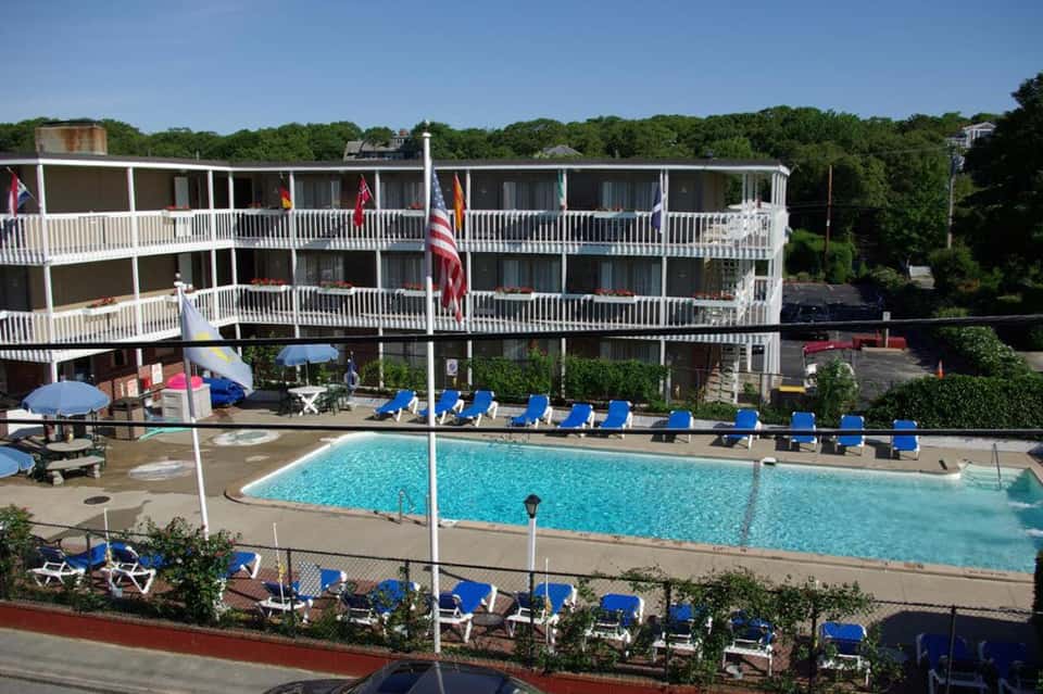 Outdoor pool with blue lounge chairs, multi-story beachfront hotel building, and palm trees