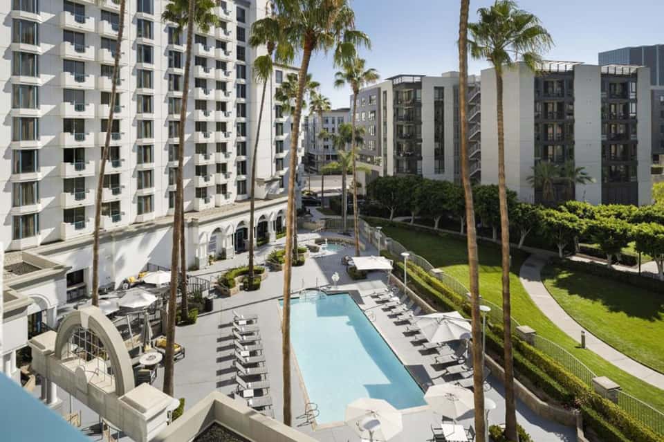 Resort courtyard with swimming pool, lounge chairs, and modern apartment buildings surrounding manicured grounds