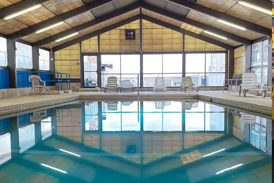 Indoor heated swimming pool with large windows overlooking city skyline
