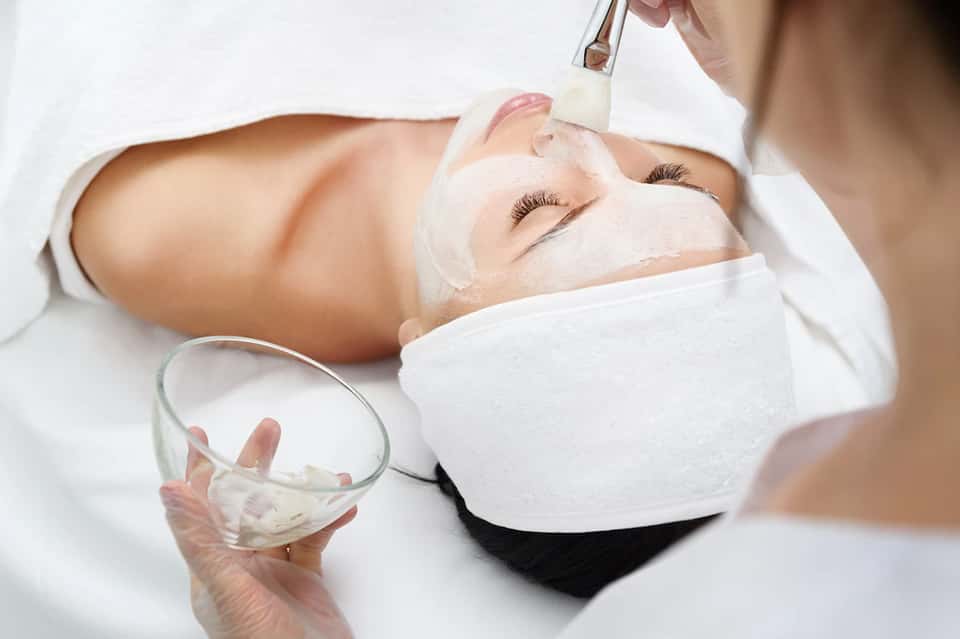 Facial spa treatment with esthetician applying mask to client's face