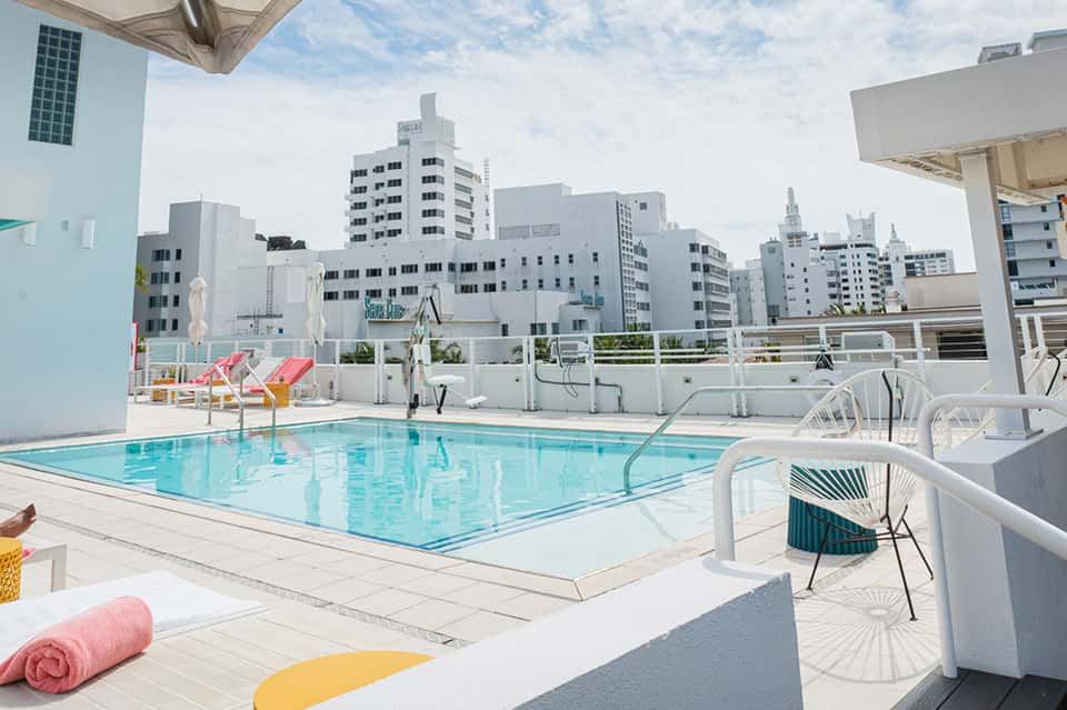 Rooftop swimming pool with lounge chairs overlooking city skyline and urban buildings
