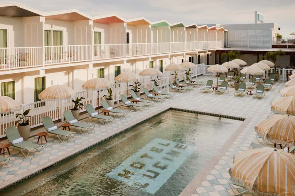 Colorful beachfront cottages with striped umbrellas surrounding a pool with spa text visible in the water