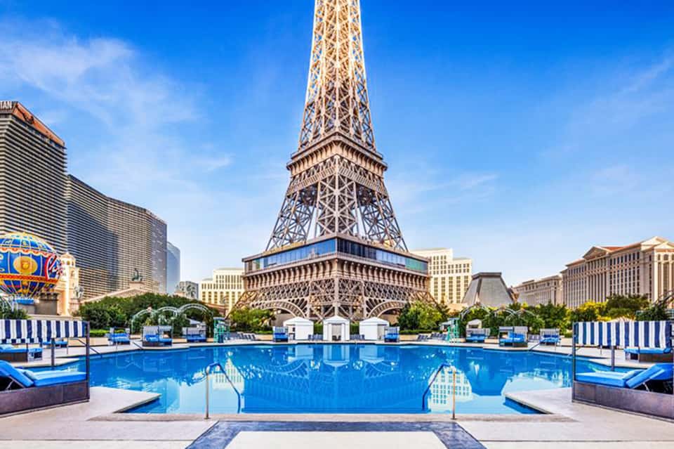 Resort swimming pool with Eiffel Tower replica backdrop and blue lounge chairs
