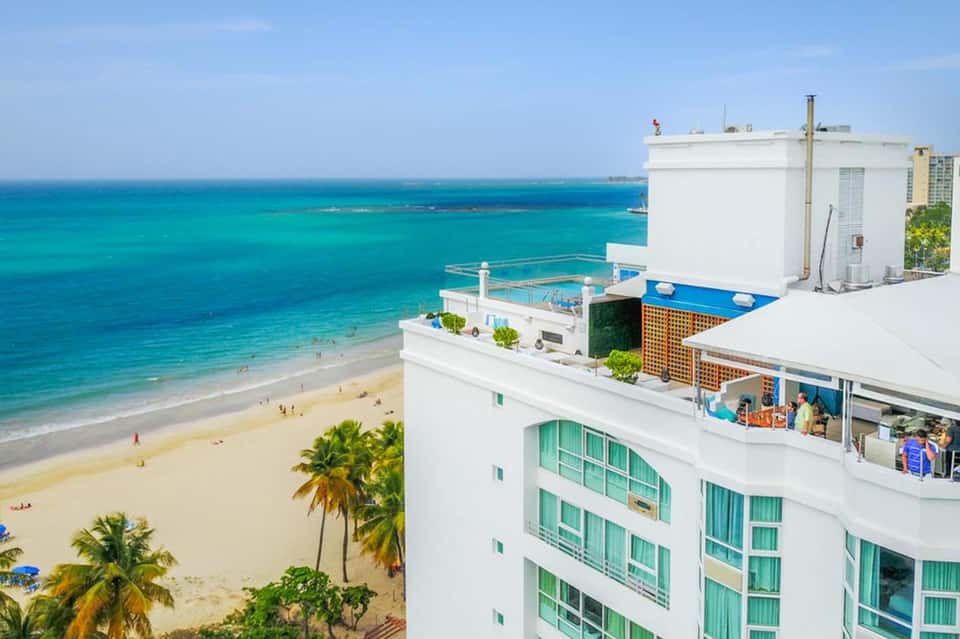 Beachfront resort building overlooking turquoise Caribbean water and white sand beach