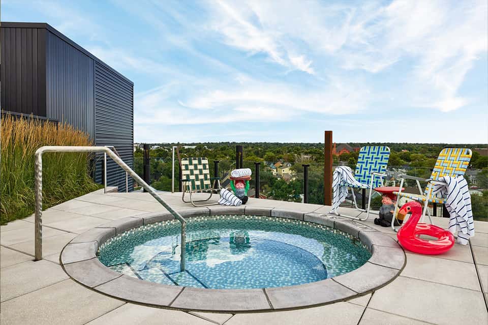 Rooftop hot tub with safety railing overlooking expansive landscape and forested terrain