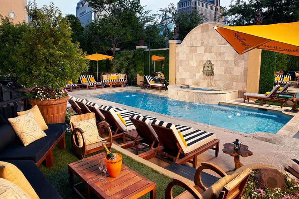 Upscale pool area with yellow umbrellas, striped loungers, and urban skyline backdrop