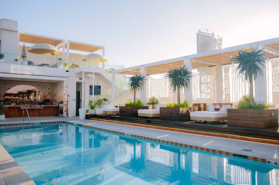 Modern rooftop pool with white pergolas, lounge seating, and contemporary architectural design