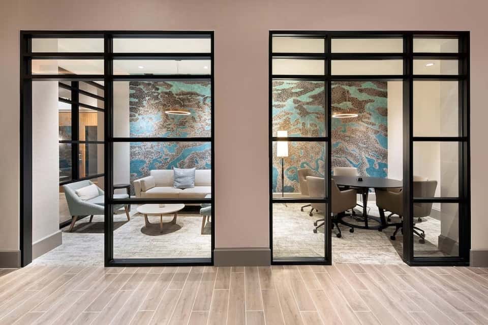 Modern glass doors with black frames opening to contemporary office and lounge spaces with map artwork