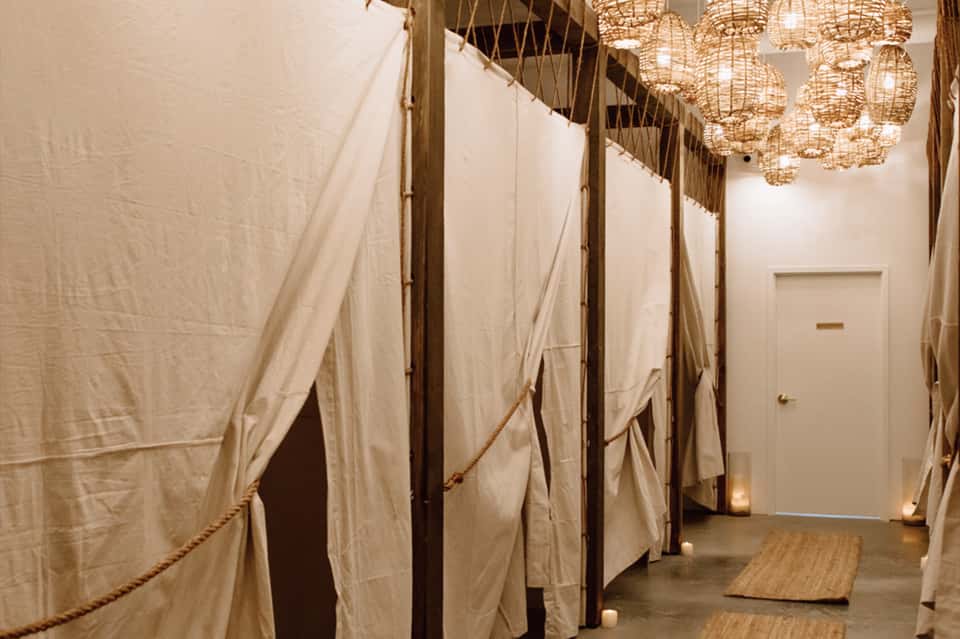 Indoor spa treatment room with cream linen curtains and woven pendant light fixtures