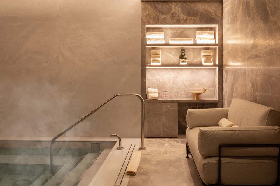 Spa relaxation room with soaking tub and illuminated wall shelving