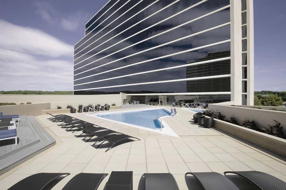 Modern high-rise building with rooftop pool, loungers, and minimalist architecture