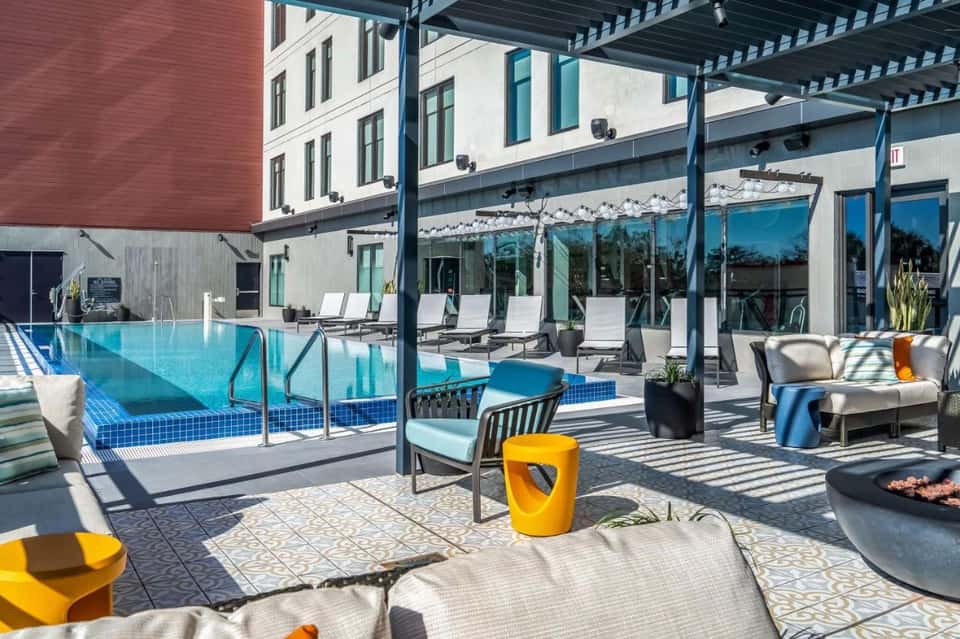 Contemporary rooftop pool with pergola, loungers, firepit, and glass windows