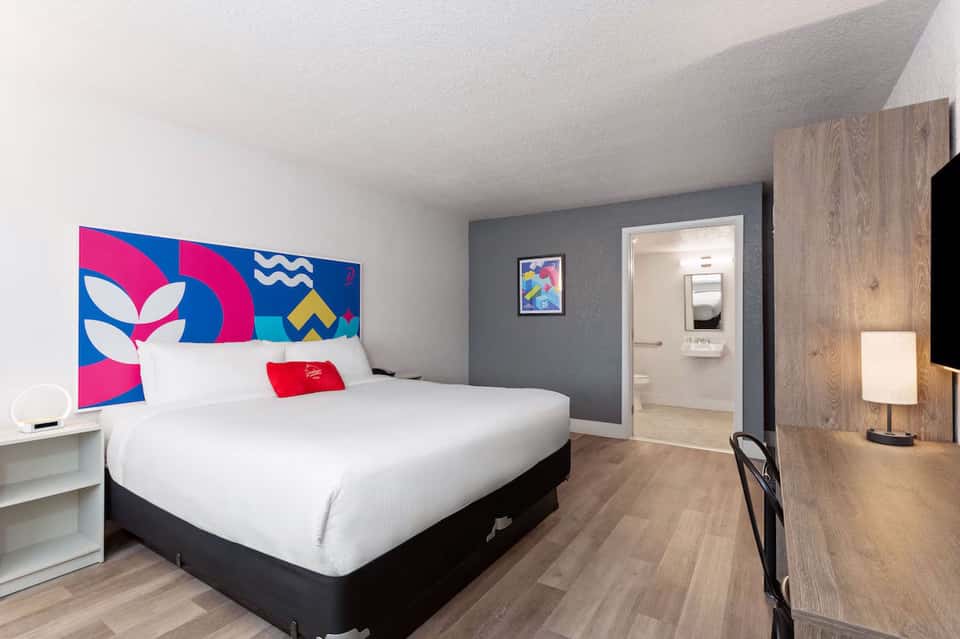 Contemporary hotel bedroom with colorful headboard art and modern furnishings