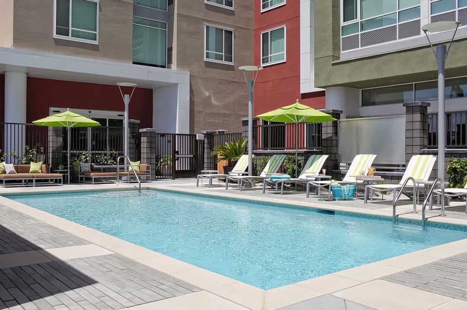 Modern apartment complex pool with bright green umbrellas and lounge chairs