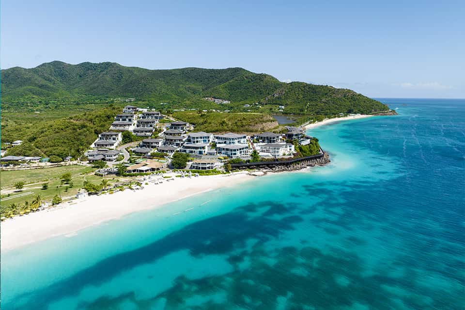 Aerial view of luxury beach resort with white villas on turquoise waters and sandy beach